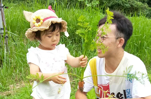 畑で野菜を手にする親子